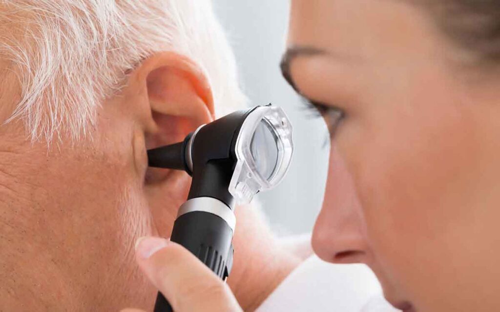 A healthcare professional examines an older persons ear using an otoscope during a medical checkup.